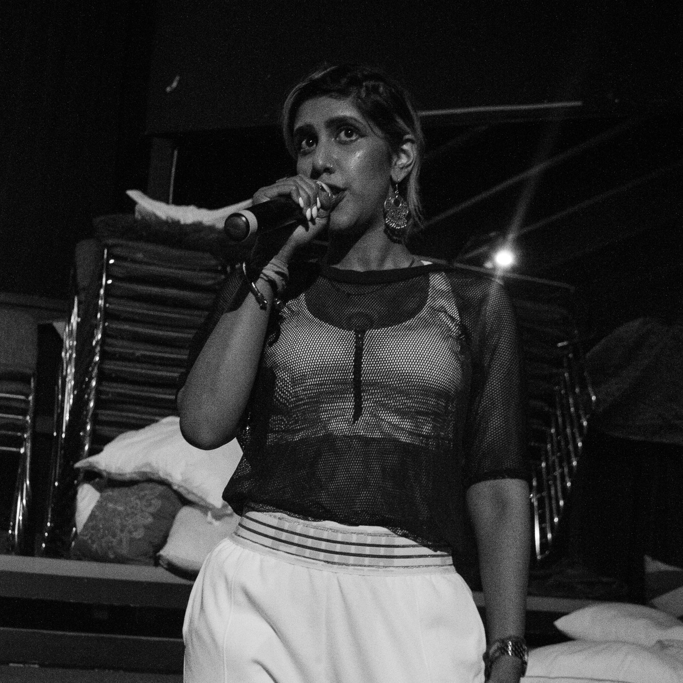 a dark-skinned individual holding a microphone and rapping on a stage